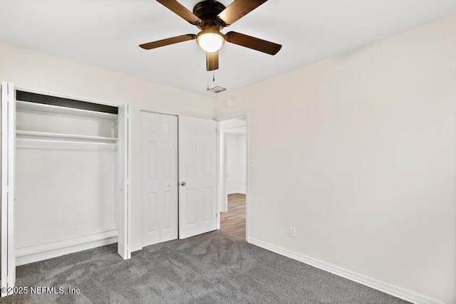 unfurnished bedroom featuring baseboards, dark colored carpet, ceiling fan, and multiple closets