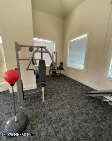 workout area featuring dark colored carpet and baseboards