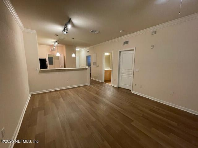 unfurnished living room with dark wood-type flooring, ornamental molding, and baseboards