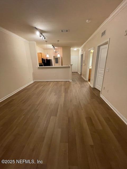 unfurnished living room with ornamental molding, dark wood-type flooring, visible vents, and baseboards