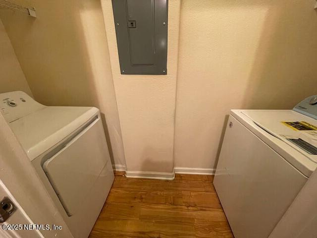 laundry room with dark wood finished floors, washer and clothes dryer, laundry area, electric panel, and baseboards