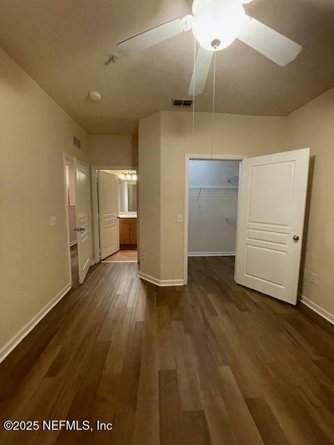 unfurnished bedroom with dark wood-type flooring, visible vents, and baseboards