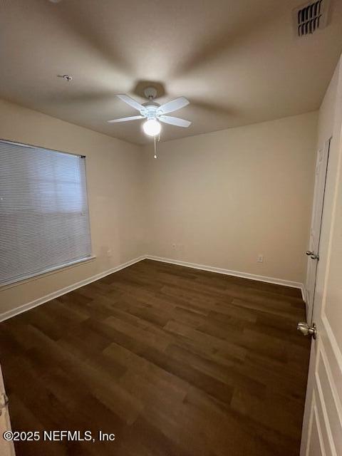 unfurnished room with dark wood-type flooring, visible vents, ceiling fan, and baseboards