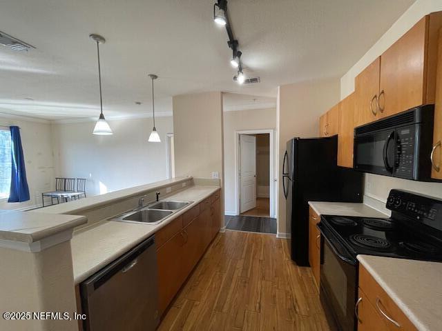 kitchen with a peninsula, a sink, light countertops, dark wood-style floors, and black appliances