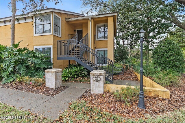 view of front facade featuring stairway and stucco siding