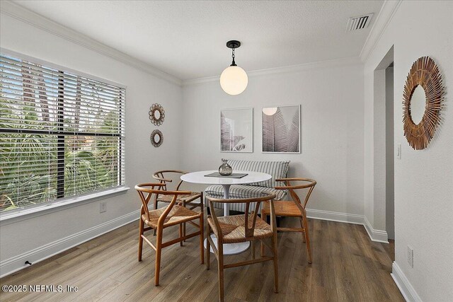 dining room featuring wood finished floors, visible vents, and crown molding