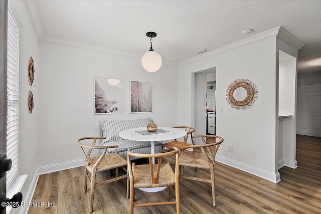 dining area featuring crown molding, visible vents, baseboards, and wood finished floors