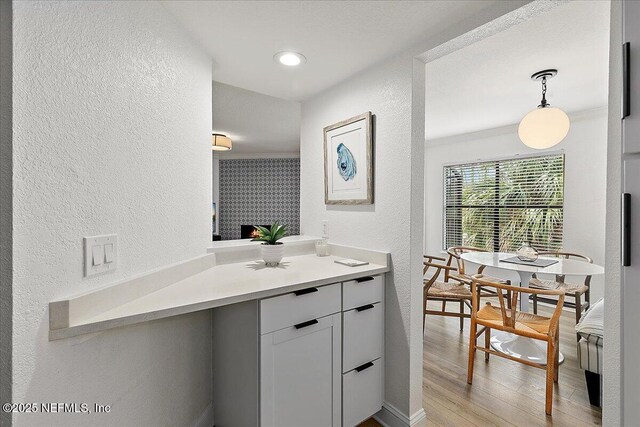 bathroom with a textured wall, vanity, baseboards, and wood finished floors