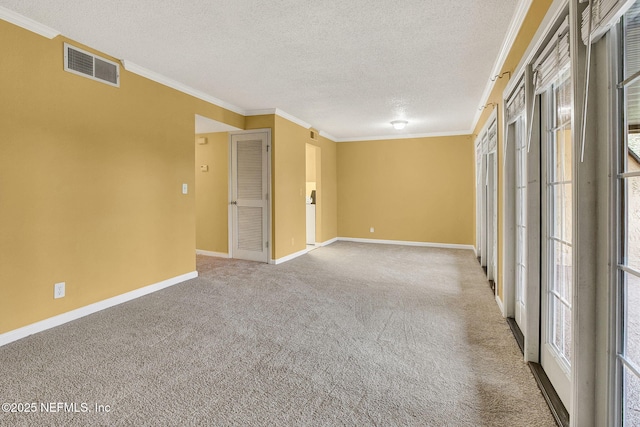 carpeted spare room featuring baseboards, a textured ceiling, visible vents, and crown molding