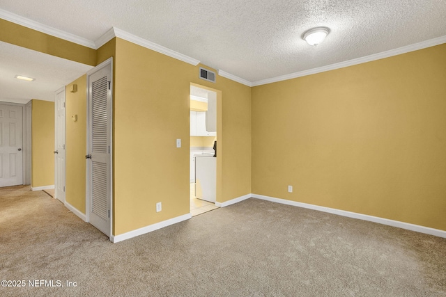 carpeted spare room featuring baseboards, washer / clothes dryer, visible vents, and crown molding