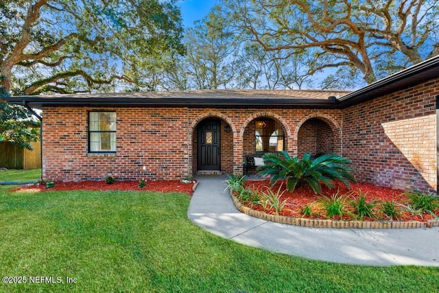 view of exterior entry featuring a yard and brick siding