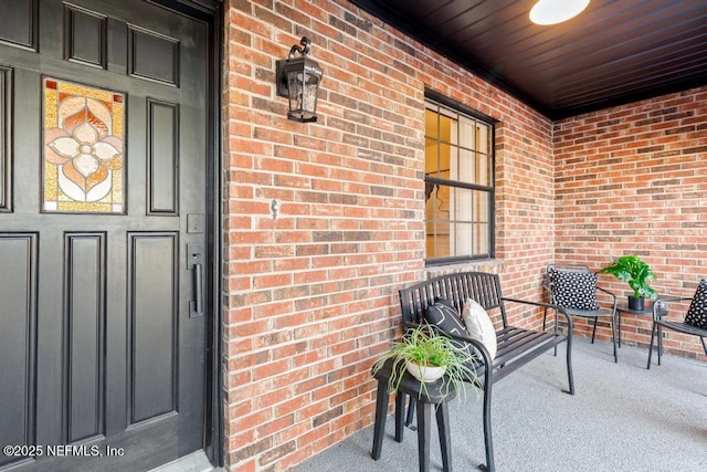 entrance to property featuring a porch and brick siding