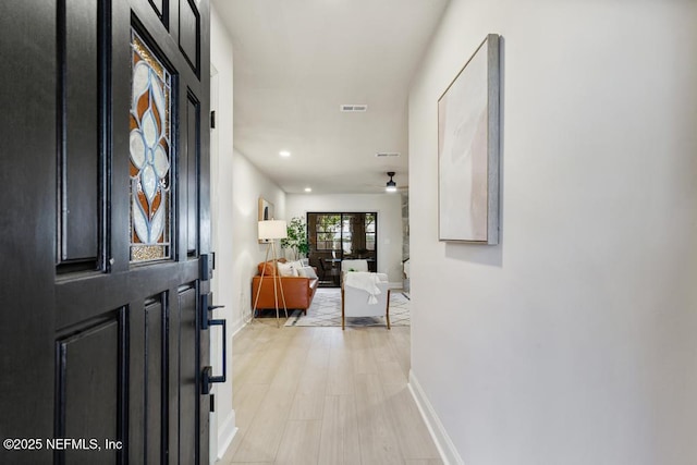 interior space featuring ceiling fan, light wood-style flooring, visible vents, and baseboards