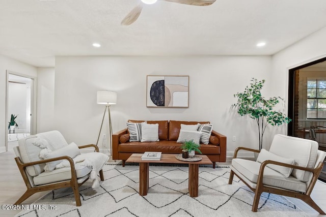 living area with light wood-type flooring, ceiling fan, baseboards, and recessed lighting