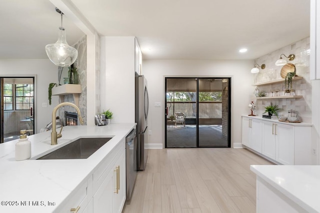 kitchen featuring stainless steel appliances, plenty of natural light, white cabinetry, and a sink