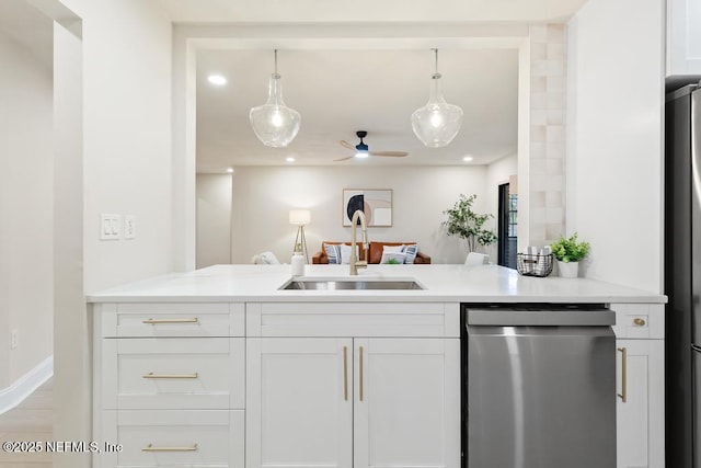 kitchen featuring white cabinets, open floor plan, light countertops, stainless steel appliances, and a sink