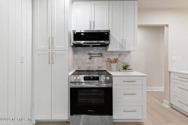 kitchen featuring light wood-style flooring, appliances with stainless steel finishes, light countertops, and backsplash