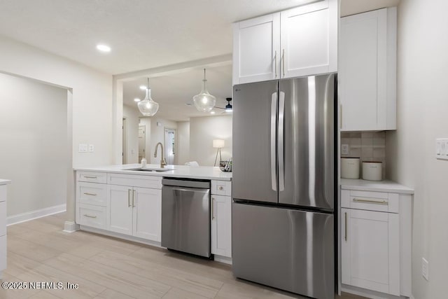 kitchen featuring light countertops, appliances with stainless steel finishes, a sink, and white cabinetry