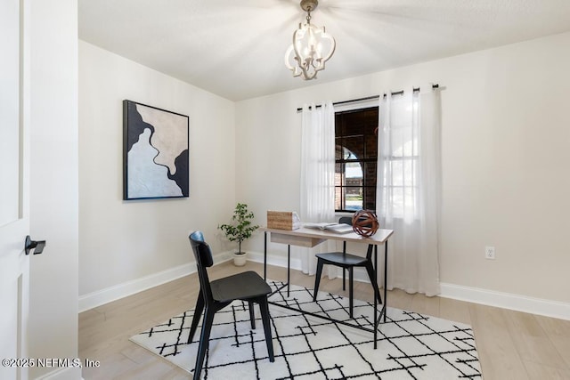 home office featuring light wood-style floors, a notable chandelier, and baseboards