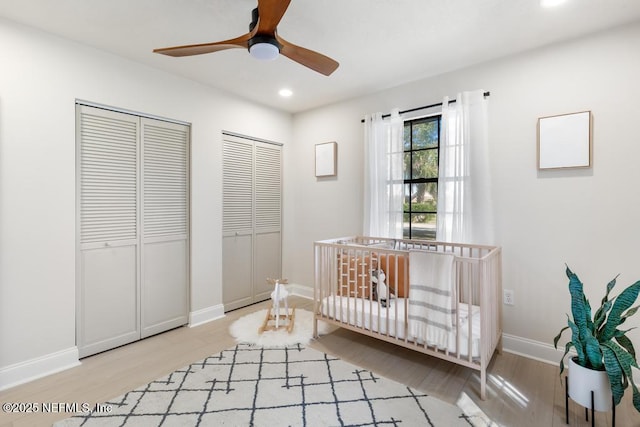 bedroom with multiple closets, recessed lighting, ceiling fan, light wood-type flooring, and baseboards