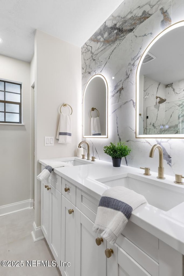 full bathroom featuring visible vents, double vanity, a sink, and a marble finish shower