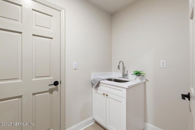 laundry room featuring a sink and baseboards