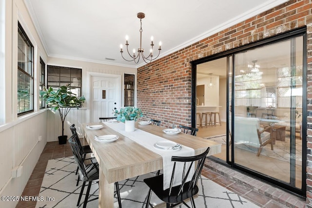 dining area with brick wall, visible vents, tile patterned floors, an inviting chandelier, and crown molding