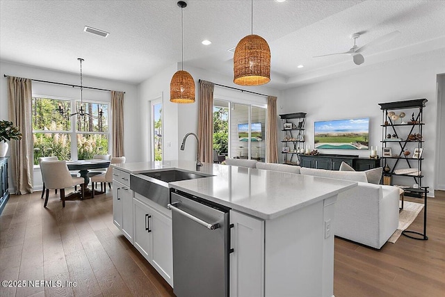 kitchen with dark wood-style flooring, a sink, open floor plan, stainless steel dishwasher, and decorative light fixtures