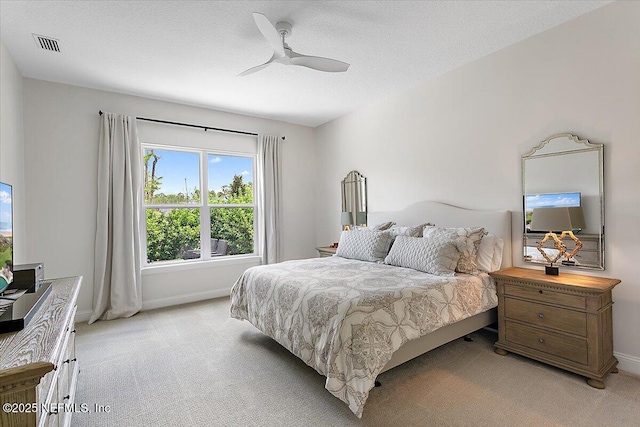 bedroom featuring visible vents, a ceiling fan, light carpet, a textured ceiling, and baseboards