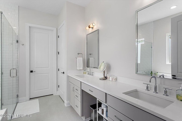 bathroom featuring double vanity, a stall shower, a sink, and tile patterned floors