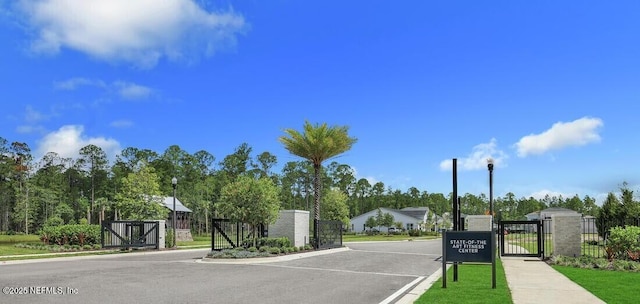 view of street featuring street lighting, a gated entry, curbs, a gate, and sidewalks