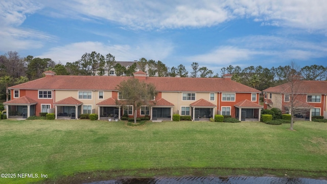 view of front of property with a sunroom, a tile roof, and a front lawn