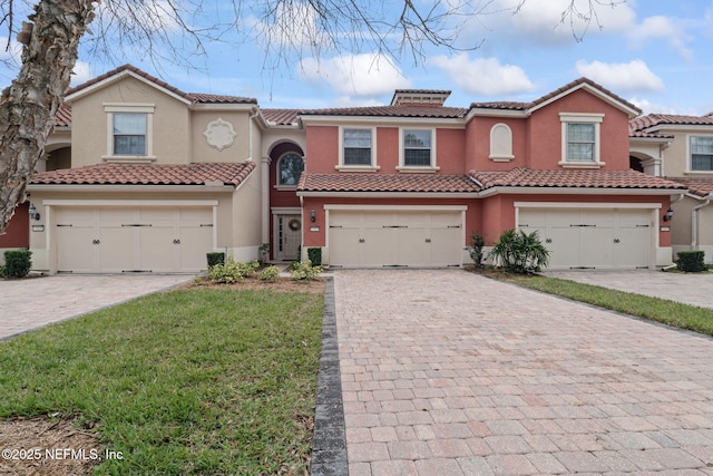 view of front of property featuring a garage, decorative driveway, a tile roof, and stucco siding