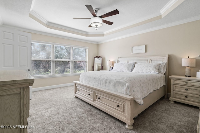 bedroom featuring carpet flooring, a ceiling fan, baseboards, ornamental molding, and a tray ceiling