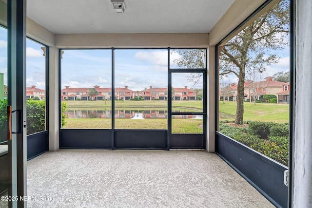 unfurnished sunroom with a water view, a residential view, and a healthy amount of sunlight