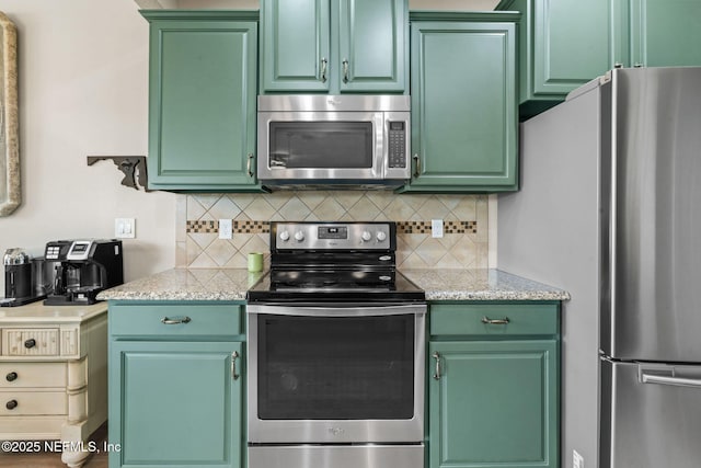 kitchen with green cabinets, tasteful backsplash, and stainless steel appliances