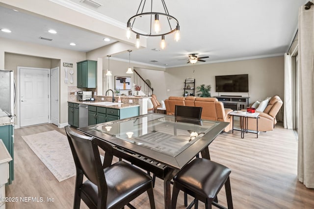 dining area with ornamental molding, ceiling fan, light wood finished floors, and stairs