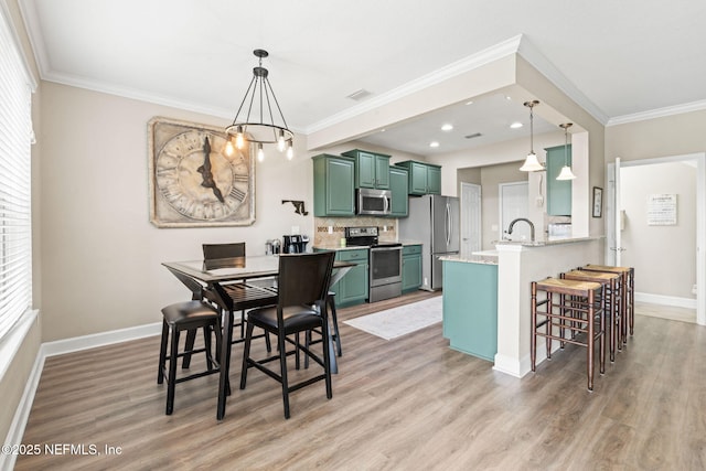 dining area with ornamental molding, light wood-style floors, and baseboards