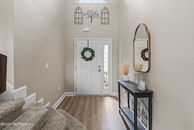 foyer with a high ceiling, wood finished floors, and baseboards