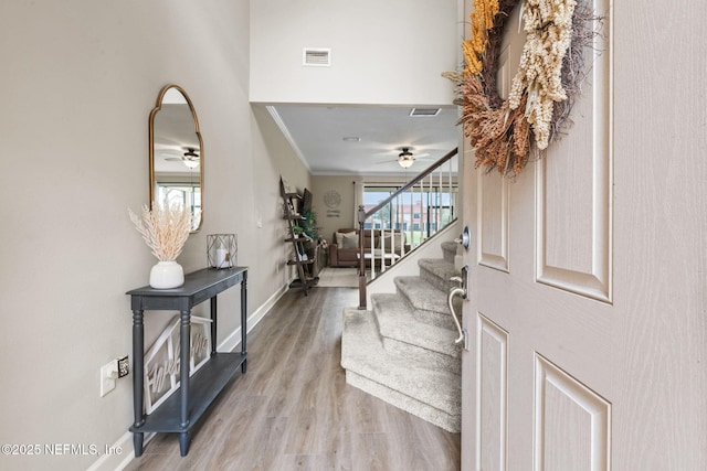 foyer with baseboards, visible vents, stairway, ornamental molding, and wood finished floors