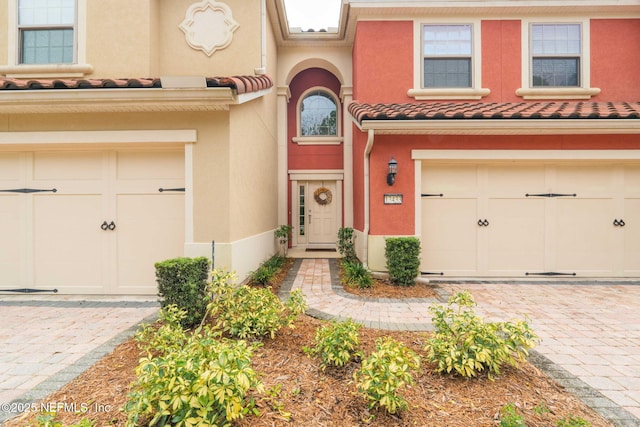 view of front of home featuring an attached garage, a tiled roof, and stucco siding