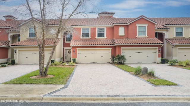 view of front facade with decorative driveway, a tile roof, and stucco siding