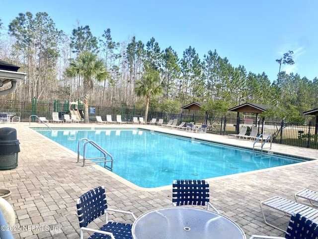 community pool featuring a patio area, fence, and playground community