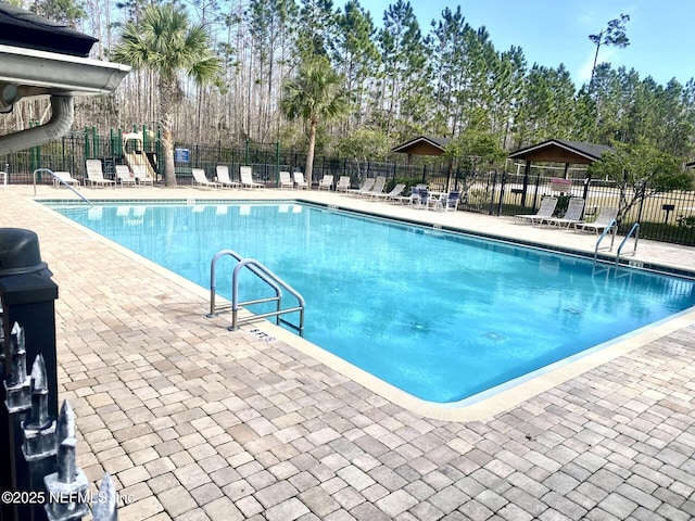 community pool featuring playground community, fence, and a patio