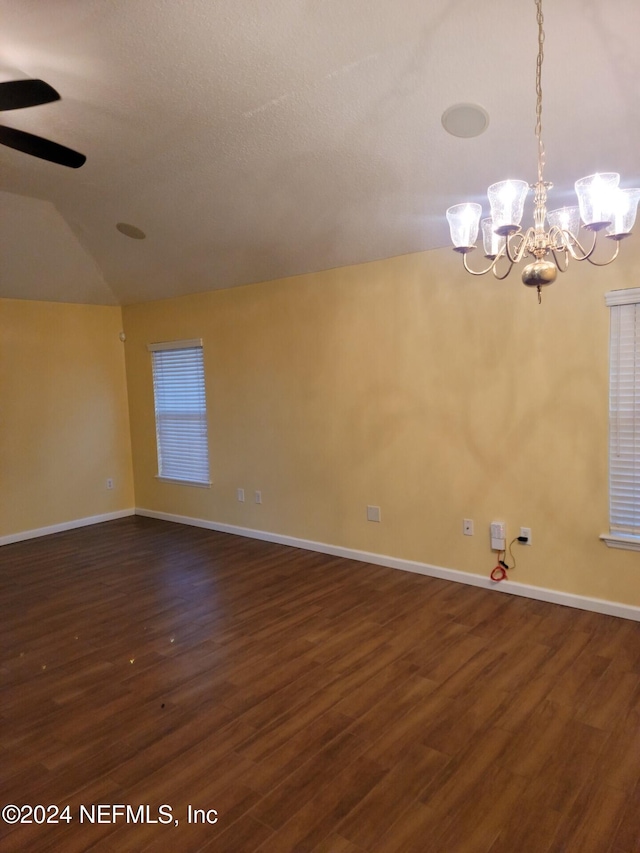 empty room with dark wood-style flooring, vaulted ceiling, baseboards, and ceiling fan with notable chandelier