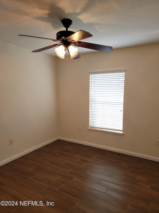 unfurnished room with ceiling fan, dark wood finished floors, and baseboards