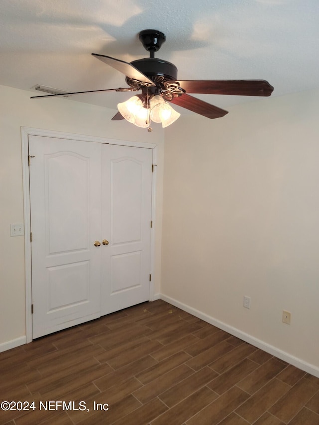 unfurnished bedroom with ceiling fan, wood finish floors, a closet, and baseboards