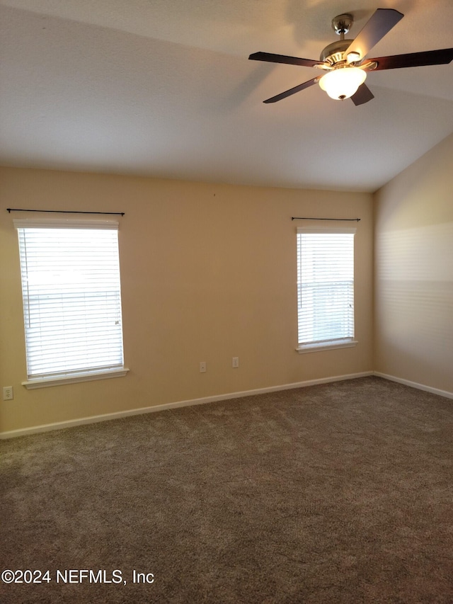 spare room with a ceiling fan, dark carpet, and baseboards