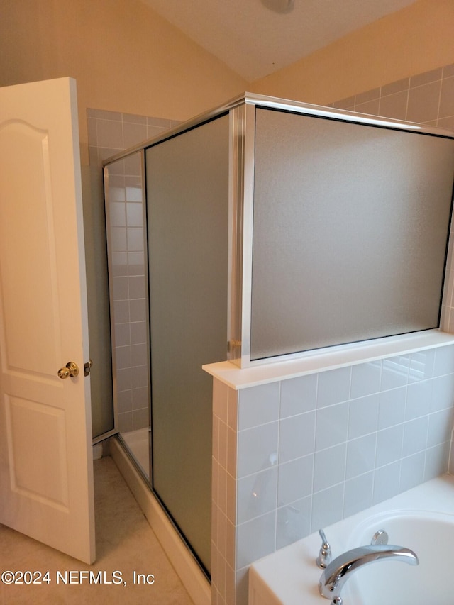 bathroom featuring a shower stall and a bath