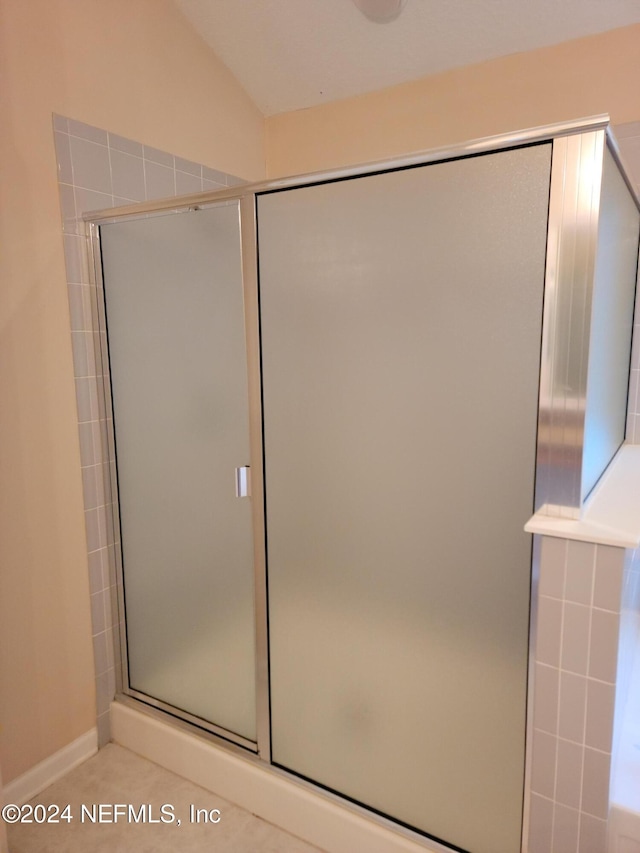 full bath featuring vaulted ceiling, a shower stall, and tile patterned floors